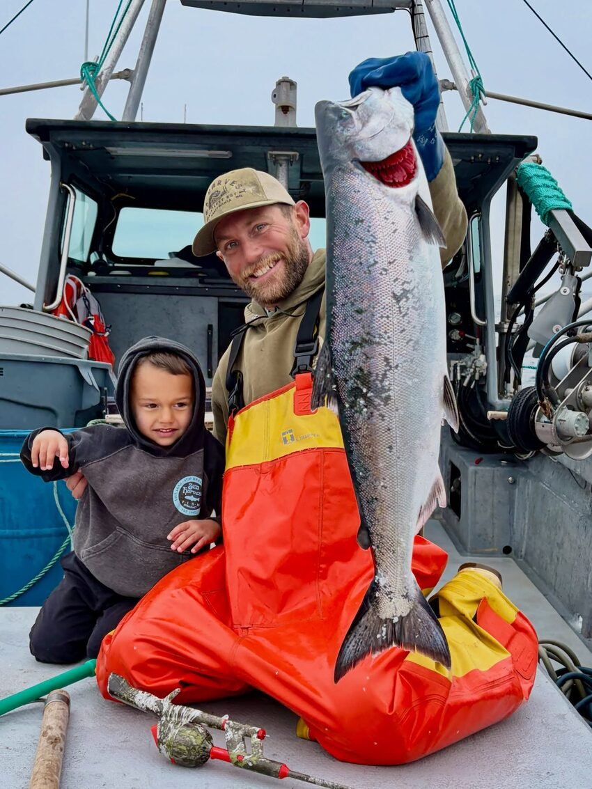 Sea Harvest fisherman and his son with a fresh-caught king salmon aboard the boat
