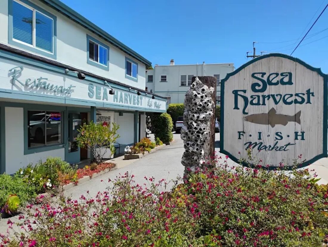 The Sea Harvest Fish Market storefront and carved sign, framed by flowers